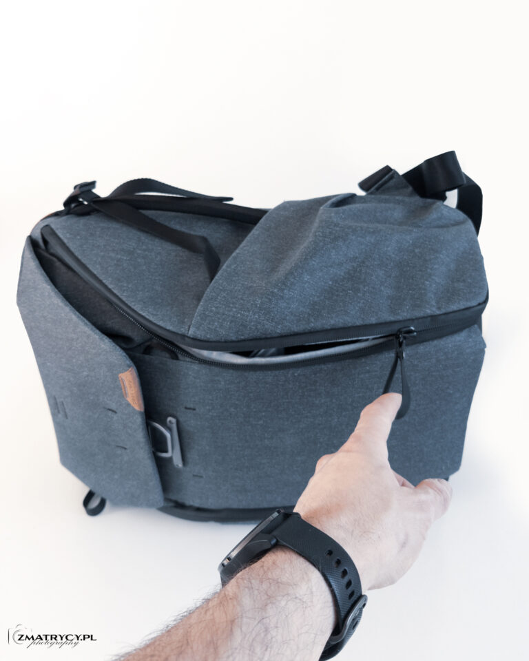 Dłoń otwierająca boczny zamek szarego plecaka Peak Design