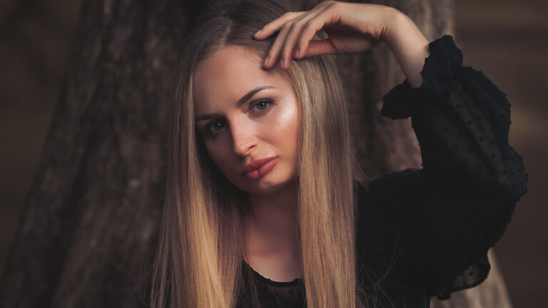 Portret kobiety z dłonią na głowie wśród drzew
