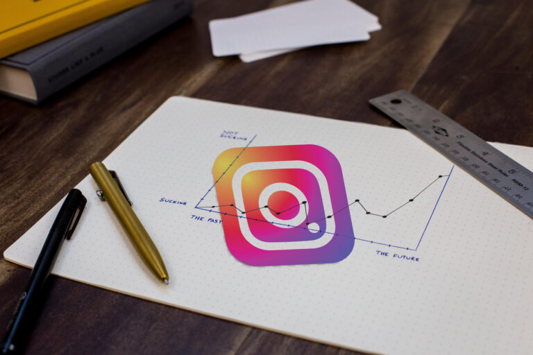 Kartka z kolorowym symbolem Instagrama obok przyborów do pisania
