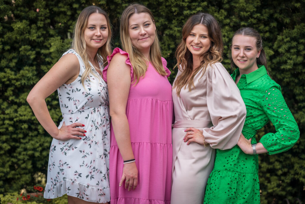 Four women posing together against greenery