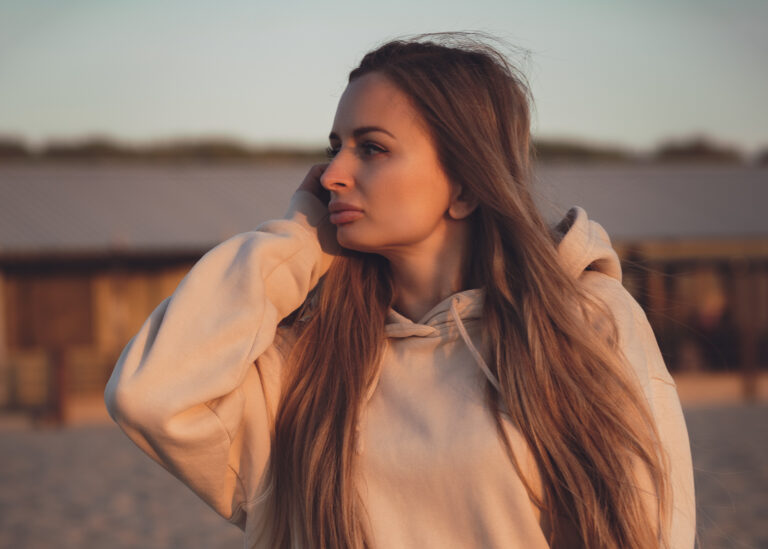 Portret kobiety w jasnym płaszczu w ciepłym świetle plenerowym