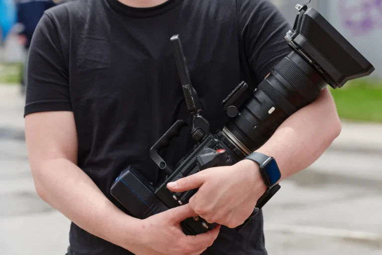 Operator trzymający kamerę obiema rękami blisko tułowia, bez gimbala